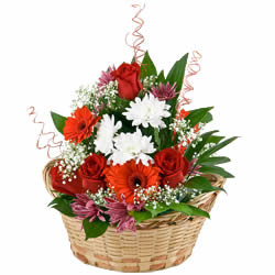Arrangement de fleurs dans un panier dans les tons rouges et blancs décoré de verdure